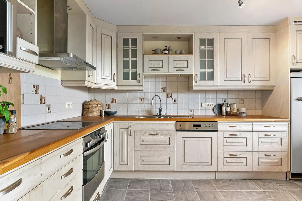 A clean kitchen with cream cabinets and a wood counter
